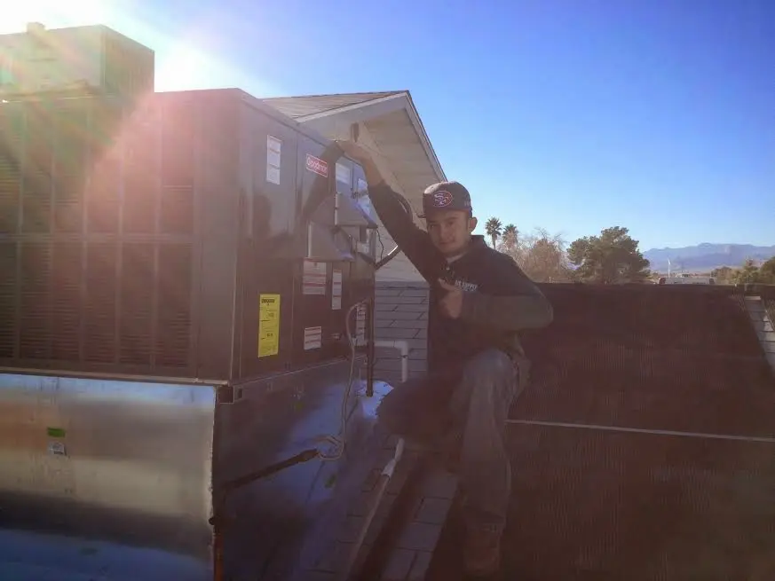 HVAC technician performing AC Tune-Up on a rooftop unit in Munford